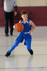 Naklejka premium Young athletic boy playing in a game of basketball