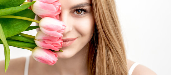 Portrait of a happy young caucasian woman with pink tulips against a white background