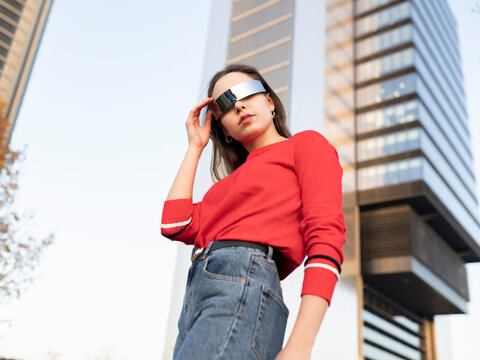 Woman wearing sunglasses standing against building in city