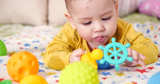 infant, childhood concept - close-up of smiling happy Baby plays with a teether. Teeth cutting. First teeth. Joy toothless 7 months baby bite, gnaws teether toy