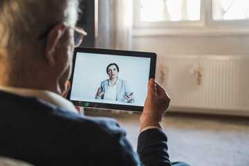 Female doctor consulting male patient on video call through digital tablet at home
