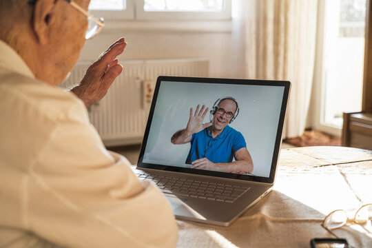 Mature man greeting senior man on video call through laptop at home