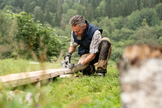 Carpenter sawing plank with circular saw