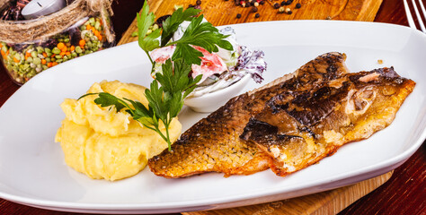 Fried fish and mashed potatoes on a white plate