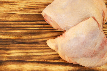 Raw chicken thighs on brown wooden board