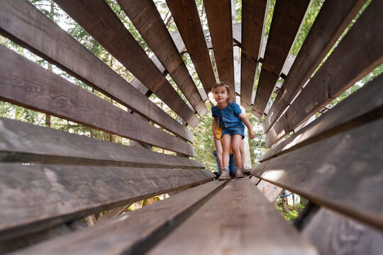 Little girl walking through tunnel made of wooden planks