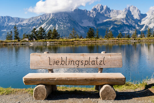 Empty wooden bench on shore of alpine lake in Kaiser Mountains