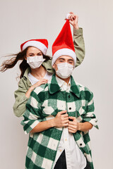 A man in a plaid shirt and a happy woman in a medical mask with a festive hat on her head