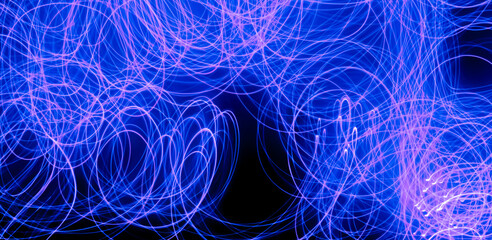 Long exposure blue lights abstract texture background. Blue lights drawing patterns on black background.