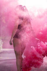 unrecognizable slim girl brunette in black bodysuit with bright pink smoke bomb. dancing, having fun. color powder. spring, summer, autumn