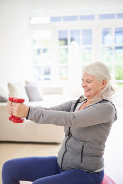 Smiling Retired Senior Woman Exercising With Dumbbells At Home