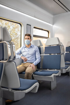 Businessman wearing protective face sitting in train during COVID-19