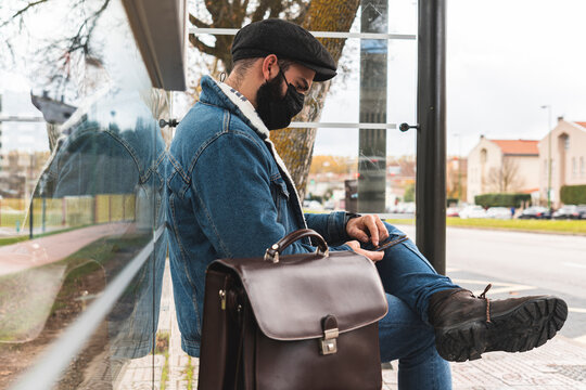 Commuter Using Smart Phone On Bus Stop During COVID-19