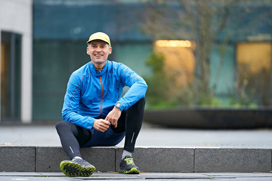 Smiling mature man wearing cap while sitting on pathway