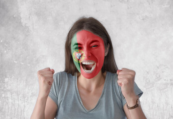 Young woman with painted flag of Portugal and open mouth looking energetic with fists up