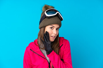 Teenager skier girl with snowboarding glasses over isolated blue background whispering something