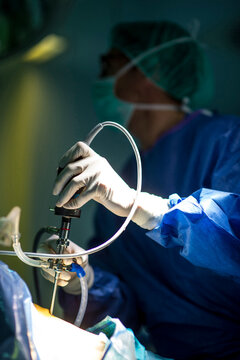 Male orthopedic surgeon operating on knee in ICU at hospital