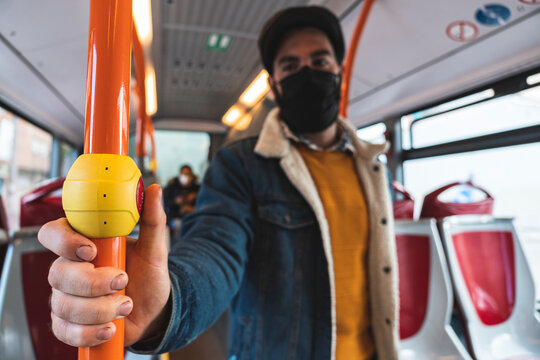 Businessman wearing protective face mask holding pole while commuting in bus