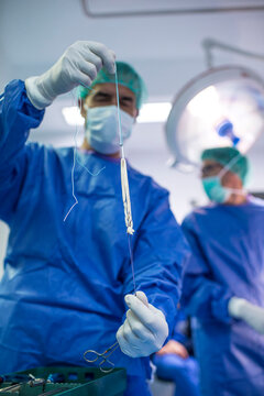Mature male surgeon holding ligament in emergency room at hospital