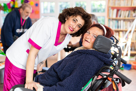 Smiling female caregiver with disabled woman at rehabilitation center