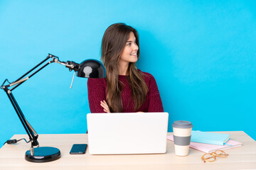 Teenager Brazilian girl with a laptop in a table looking to the side