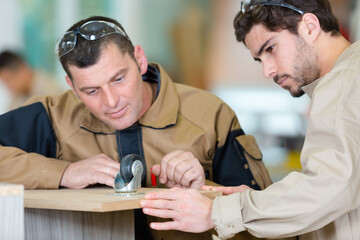 man working in workshop with apprentice