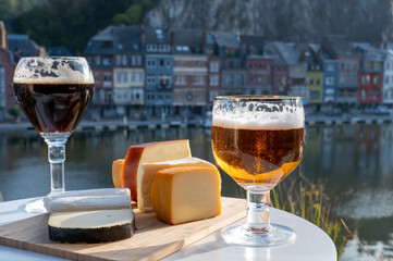 Drinking of dark and strong Belgian abbey beer with cheeses with nice view on Maas river and town Dinant, Belgium
