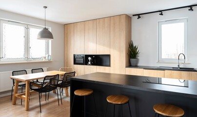 Bright interior of luxurious kitchen with granite kitchen island, stylish chairs and wooden furniture. Dining room in modern apartment with window. 