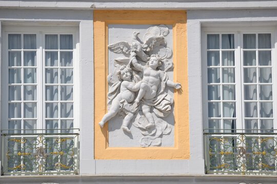 Facade development with figures like angels dancing and an eagle painted white between two windows with checkered divisions