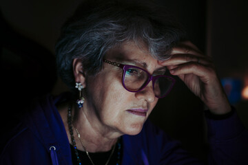 Close-up of senior teacher with head in hand working at home