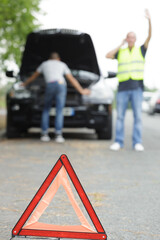 man asking for help next to a broken car