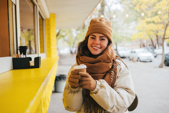 Happy woman at street cafe with disposable coffee cup during autumn