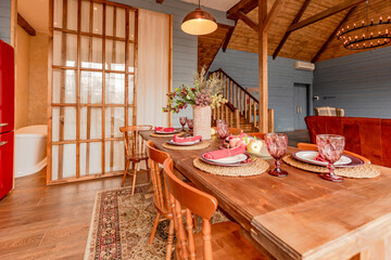 cozy all wooden interior of a country house in a wooden design. spacious living room with kitchen area with large windows. bedroom on the second floor.