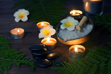Fototapeta na wymiar Black stones for hot massage on a table surrounded by burning candles
