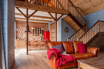 Fototapeta na wymiar cozy all wooden interior of a country house in a wooden design. spacious living room with kitchen area with large windows. bedroom on the second floor.