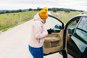 woman with a cold face, looking at her cell phone, with the car stopped and the driver's door open