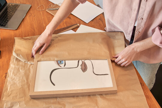 Female freelancer preparing package in brown paper while working at home