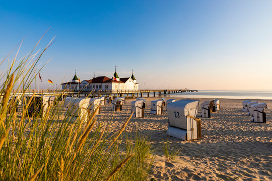 Germany,&not;&dagger;Mecklenburg-Western&not;&dagger;Pomerania, Ahlbeck, Hooded beach chairs on sandy coastal beach with bathhouse in background