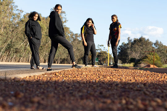 four teenagers dressed in black standing on the edge of a road