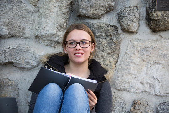 Teenage girl with glasses writing in notebook