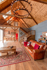 cozy all wooden interior of a country house in a wooden design. spacious living room with kitchen area with large windows. bedroom on the second floor.