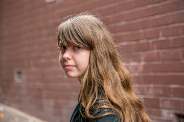 Young teen girl with a fringe in an alleyway looking sad