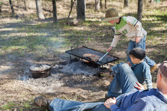 Boys cooking and relaxing around the campfire