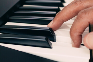 Fototapeta premium Close-up of a finger playing the keyboard of a piano, selective focus. Music concept