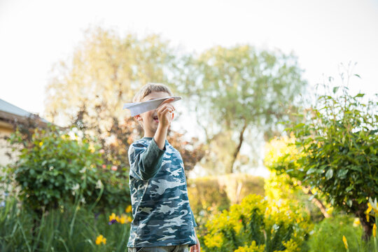 Six year old boy flying paper planes in the garden