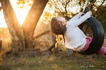 Happy kid playing in backyard on tyre swing