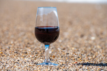 Tasting of different fortified dessert ruby, tawny port wines in glasses on sandy beach with view on waves of Atlantic ocean near Vila Nova de Gaia and city of Porto, Portugal