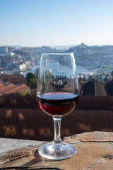 Tasting of different fortified dessert ruby, tawny port wines in glasses with view on Douro river, porto lodges of Vila Nova de Gaia and city of Porto, Portugal