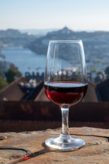 Tasting of different fortified dessert ruby, tawny port wines in glasses with view on Douro river, porto lodges of Vila Nova de Gaia and city of Porto, Portugal