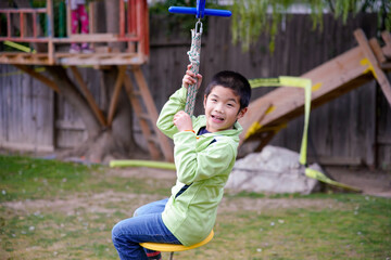 The boy playing zip lining in the backyard